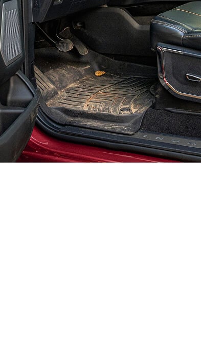 A WeatherTech FloorLiner HP covered in dirt installed in a vehicle.