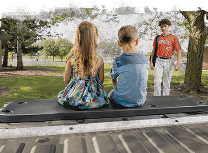 Children sitting on a WeatherTech Tailgate Cushion in a park.