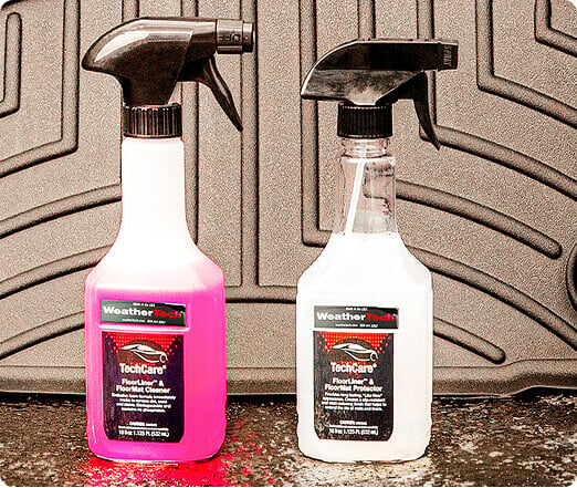WeatherTech TechCare products resting on asphalt with a FloorLiner behind them.