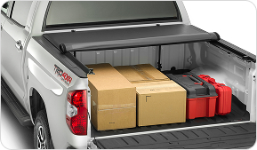 back of truck with tailgate flap open and truck bed cover halfway rolled up to show boxes