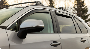 Side angle of a champagne-colored S U V with side window deflectors in sunset light 